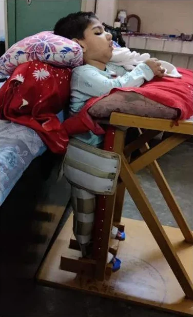 A child supported in a wooden standing frame