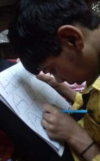 A boy bent over a worksheet, writing carefully