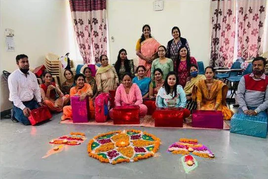 Staff and families seated behind a Diwali rangoli